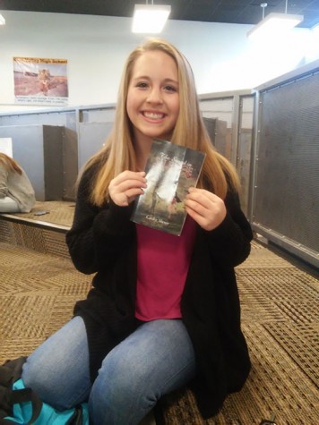 Sophomore Carley Sherer holding up her book “The Sound in Silence” in the fixed forum.