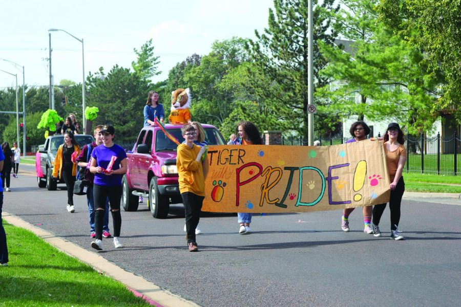 Holding up a banner, Gay Straight Alliance walks together in the Homecoming parade. “It was really empowering,” junior Lauren Mohar said. “I like being in a group of like-minded people.”